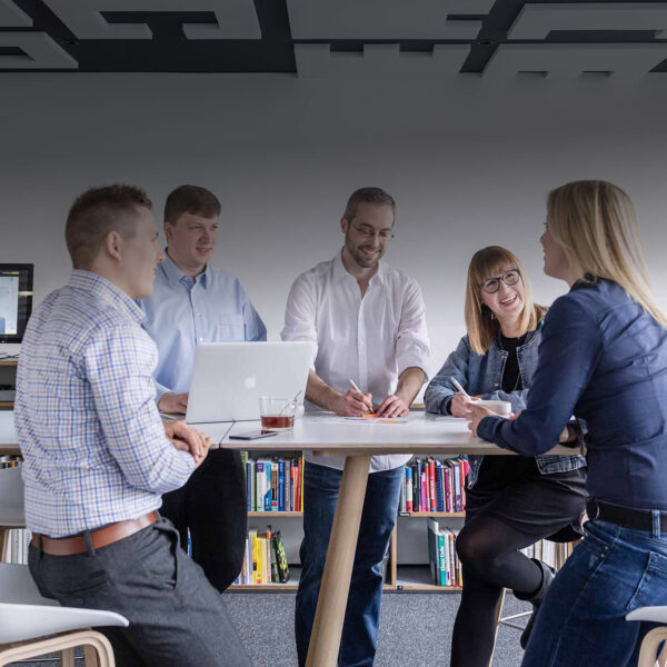 Changitors_Start_Erfolg Fünf Personen bei einem kreativen Meeting an einem Stehtisch – Zusammenarbeit in einem modernen Büro